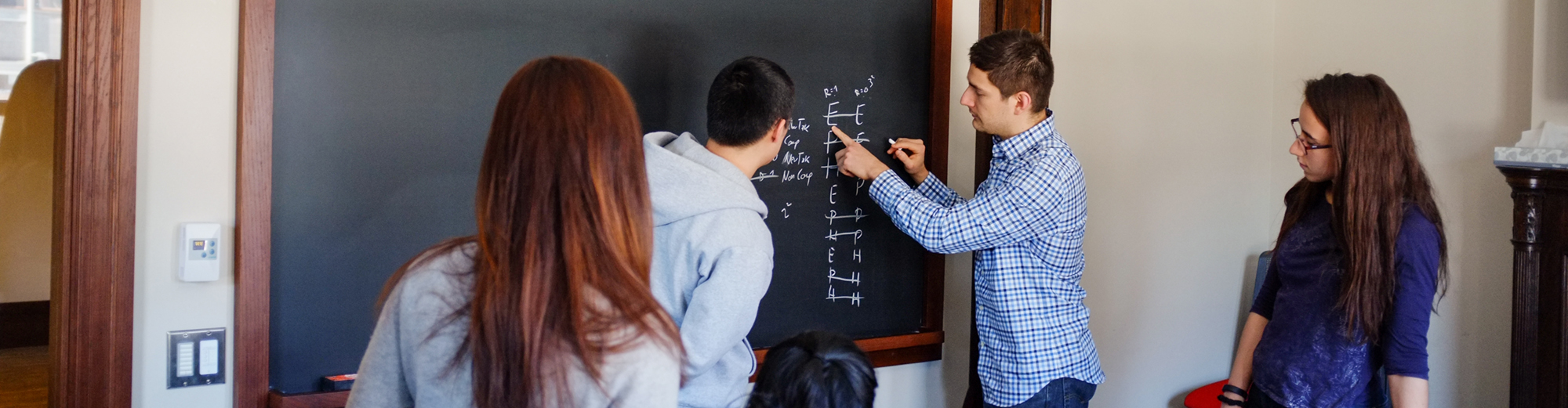 Teacher and students working on a chalkboard.