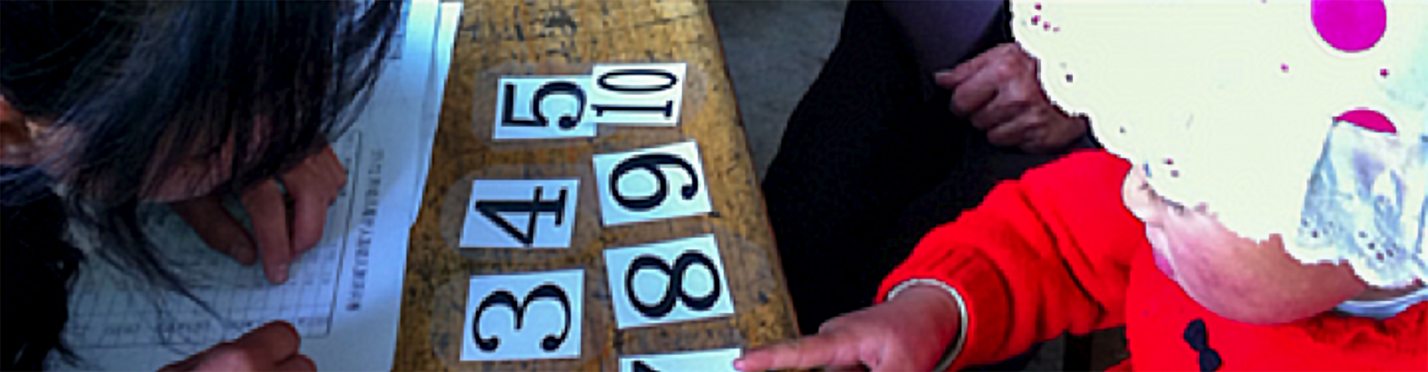 Young child pointing to a numbered piece of paper.